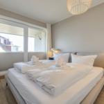 Schlafzimmer mit großem Bett, Fenster und Nachttisch.