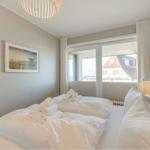 Schlafzimmer mit Doppelbett, Fenster und Bild an der Wand.
