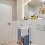 Badezimmer mit Waschbecken, Spiegel, Toilette und Handtuchhalter.