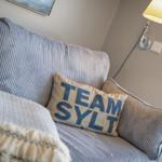 Ein Sofa mit Kissen und einer Lampe an der Wand.