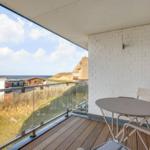 Terrasse mit Tisch und Stühlen, Blick auf Strand und Strandhaus.