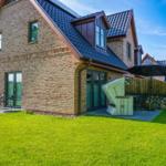 Ein Haus mit Backsteinfassade und Terrasse mit Gartenmöbeln.