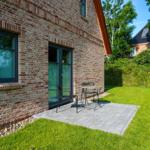 Terrasse mit Tisch und Stühlen vor Backsteinhaus mit Grasfläche