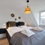 Schlafzimmer mit Doppelbett, Fenster und Deckenleuchte.