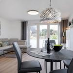 Essbereich mit runder Tisch und Stühlen. Wohnbereich mit Sofa und Fenster.