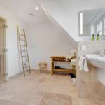 Badezimmer mit Dusche, Waschbecken und Sauna im Hintergrund.