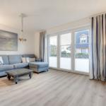 Wohnzimmer mit Sofa, Couchtisch und großen Fenstern.