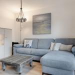 Ein Wohnzimmer mit grauem Sofa, Holztisch und Wandbild.
