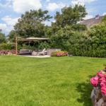 Large garden with seating area, sunshade, and blooming roses.