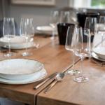 Wooden table set with dishes and glasses for meals