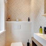 Bathroom with window, sink, and toilet. Walls with woven pattern.