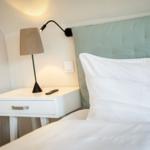Bed headboard with pillow, nightstand with lamp and remote