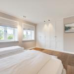Bedroom with two beds, white closets, and wooden floor.