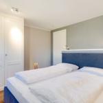 Bedroom with double bed, blue headboard, and white walls.