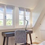Bedroom with desk, windows, and closet.