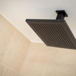 Square shower head with perforated surface mounted on ceiling.