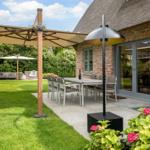 Terrace with table, chairs, umbrella, and garden house. Lawn and flowers in foreground.