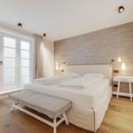 Bedroom with large bed, wooden floor, and window with view.