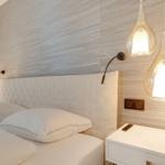 Bedroom with white bed, wood wall, and hanging lamps.