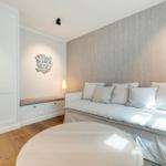 A room with sofa, round table, and white cabinets against the wall.