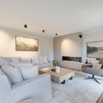 Living room with sofa, armchair, fireplace, and wall art.