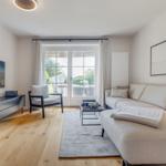 Wohnzimmer mit Sofa, Sessel und TV. Durchgang zur Terrasse.