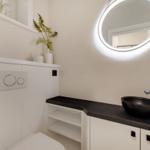 Badezimmer mit Waschbecken, Spiegel und Toilette