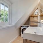 Badezimmer mit Waschmaschine, Waschbecken und Fenster