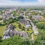 Dorf mit strohgedeckten Häusern und grünen Wiesen
