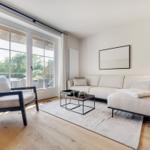 Wohnzimmer mit Sofa, Sessel und Tisch vor großem Fenster