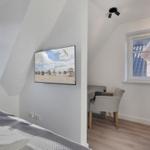 Schlafzimmer mit Bett, Fernseher und Arbeitsplatz. Dachgeschoss mit Fenstern.