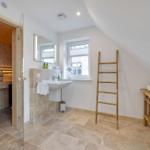 Bad mit Dusche, Waschbecken und Sauna. Holzregal und Leiter sind vorhanden.