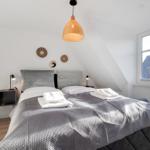Schlafzimmer mit Doppelbett, Fenster und Deckenleuchte.