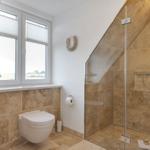 Badezimmer mit Dusche, WC und Fenster mit Blick.
