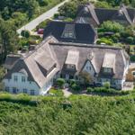 Haus mit strohgedecktem Dach und gepflegtem Garten