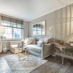 Wohnzimmer mit Sofa, Tisch, Stuhl und Fenster. Wandspiegel und Deckenleuchte sichtbar.