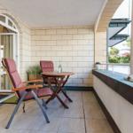 Terrasse mit Tisch, zwei Stühlen und Pflanzen. Durchgang zur Wohnung.