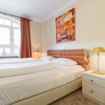 Schlafzimmer mit Doppelbett, Fenster, Gemälde und Nachttisch.