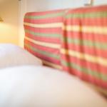 Bettkopf mit gestreifter Abdeckung und Stehlampe im Hintergrund.