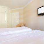 Schlafzimmer mit Bett, Kleiderschrank und Wandfernseher.