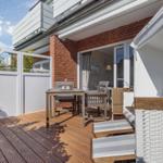 Terrace with table, chairs, and garden shed. View into the house through glass doors.