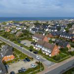 Aerial view of a coastal town with red brick houses and a sea in the background.