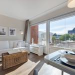 Living and dining area with view of balcony and garden.