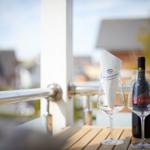 Auf der Terrasse stehen zwei Weingläser und eine Flasche Rotwein.