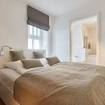 Schlafzimmer mit Bett, Fenster und angrenzender Badewanne.