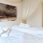Schlafzimmer mit Bett, Handtüchern und Wandbild von Bergen.