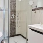 Dusche mit Glaswand, Waschbecken und Toilette in moderner Einrichtung.