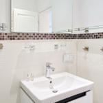 Badezimmer mit Waschbecken, Spiegel und Mosaikfliesen