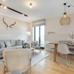 Living and dining area with sofa, table and chairs, and deer antlers on the wall.