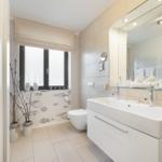 Bathroom with sink, mirror, toilet, and window.